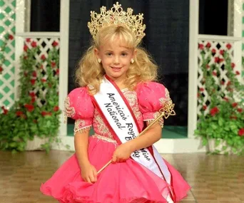 A young girl in a pageant dress and crown, wearing a sash labeled "America's Royal Miss National Beauty."