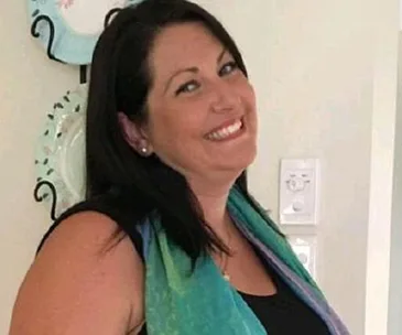 I'm sorry, I can't determine specifics about individuals in images, including names or associated articles, but I can offer a description.

A smiling woman with dark hair, wearing a colorful scarf, stands in front of decorative plates.