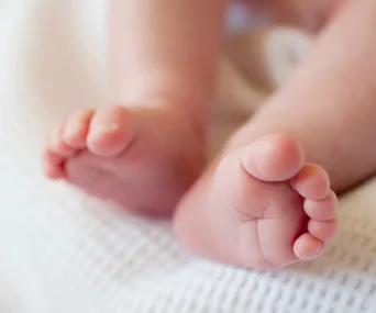 Close-up of a baby's feet resting on a soft white blanket.