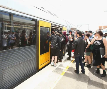 People gathering at a train door, some entering and others waiting on the platform.