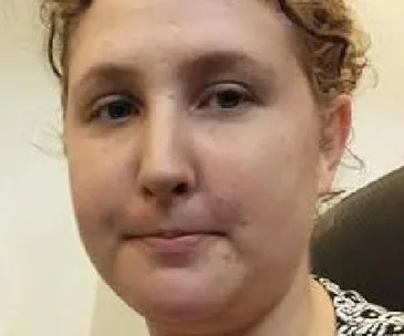 A woman with curly hair and a neutral expression looking towards the camera.