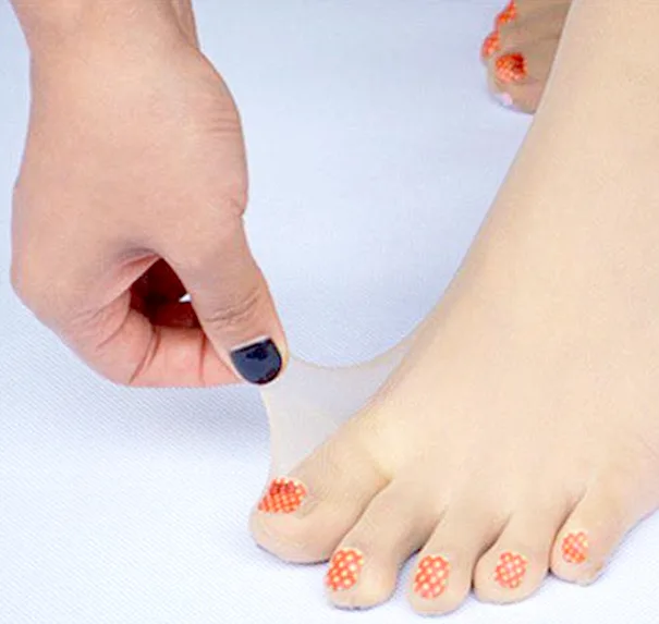 Webbed stockings covering feet with painted toenails, being pulled gently by a hand with black-painted nails.