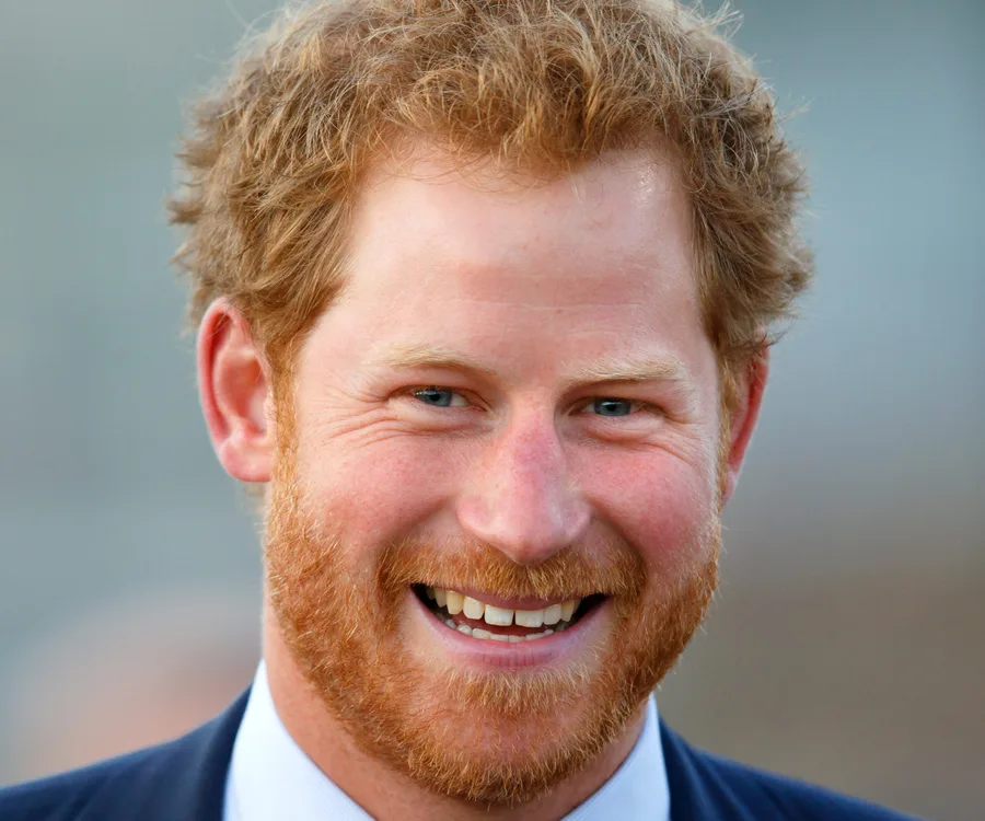 A person with red hair and a beard, smiling broadly while wearing a suit.