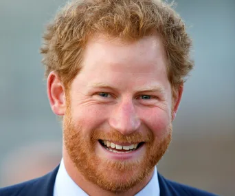 A person with red hair and a beard, smiling broadly while wearing a suit.