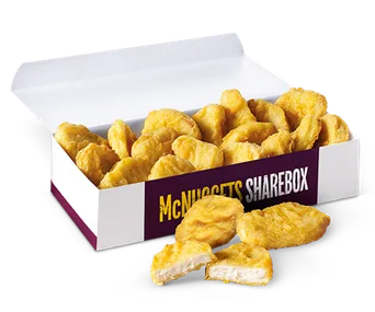 Open McDonald's ShareBox with a pile of golden chicken McNuggets spilling out, with a few pieces on the side.