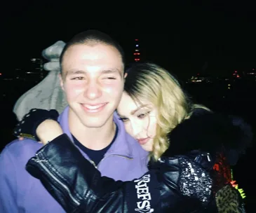Madonna hugging her son Rocco at night during his 16th birthday celebration with city lights in the background.