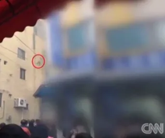 A building with people below; a red circle indicates where someone is dropping from an upper floor.