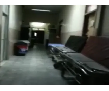 Hospital corridor with stretchers against a wall, dimly lit, suggesting an eerie atmosphere.