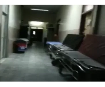 Hospital corridor with stretchers against a wall, dimly lit, suggesting an eerie atmosphere.