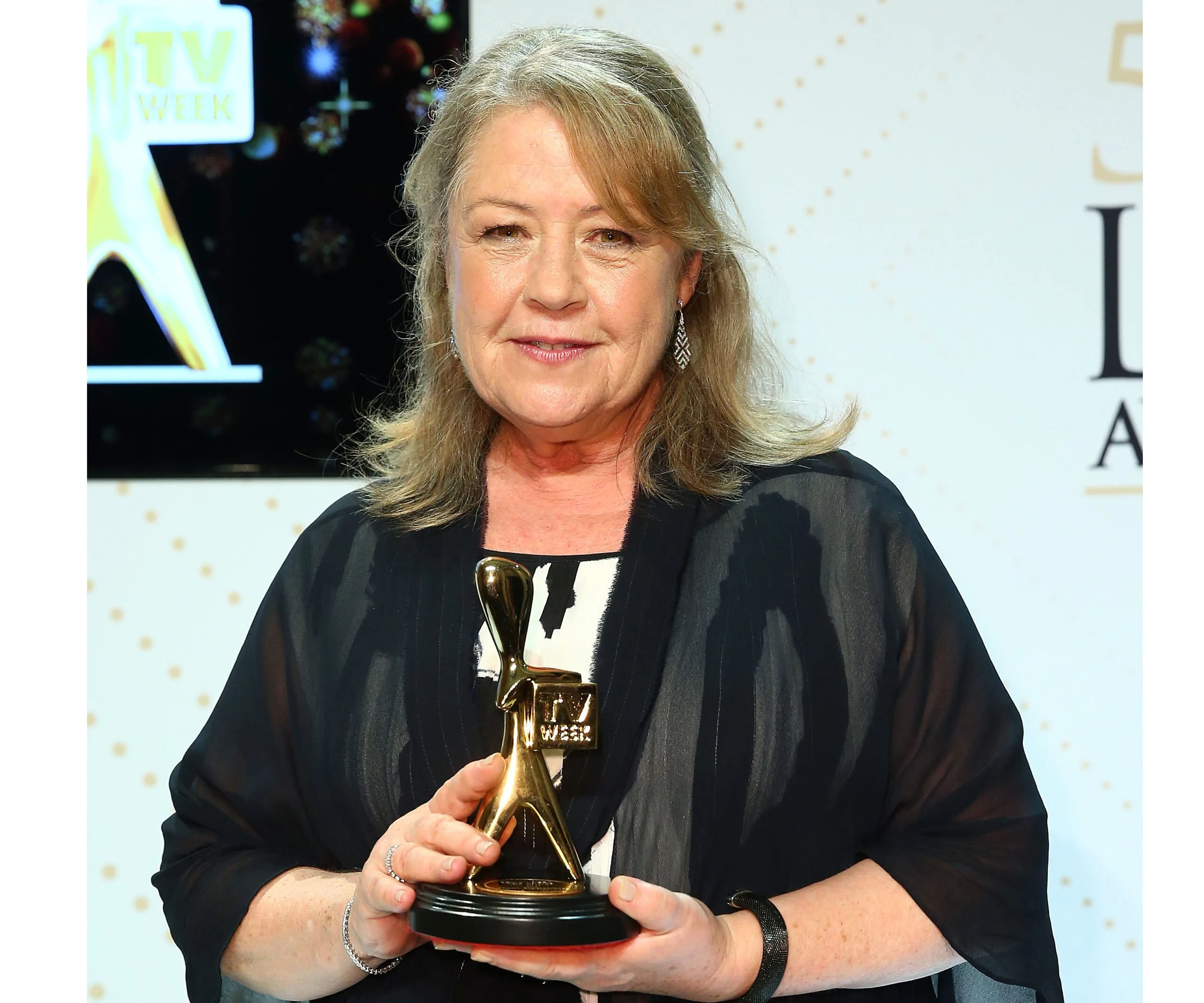 A woman holding a Logie award, with a backdrop featuring the TV Week logo.