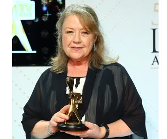 A woman holding a Logie award, with a backdrop featuring the TV Week logo.