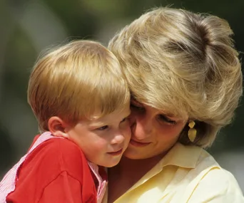 Mother hugging young child affectionately outdoors.