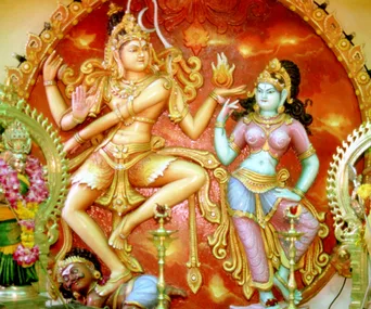 A colorful depiction of Hindu deities Shiva and Parvati in a traditional dance pose, surrounded by intricate carvings.