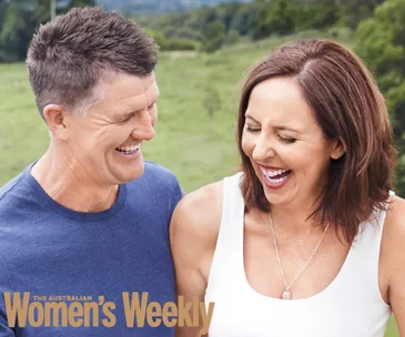 Man and woman smiling and laughing together outdoors, appearing joyful and comfortable.