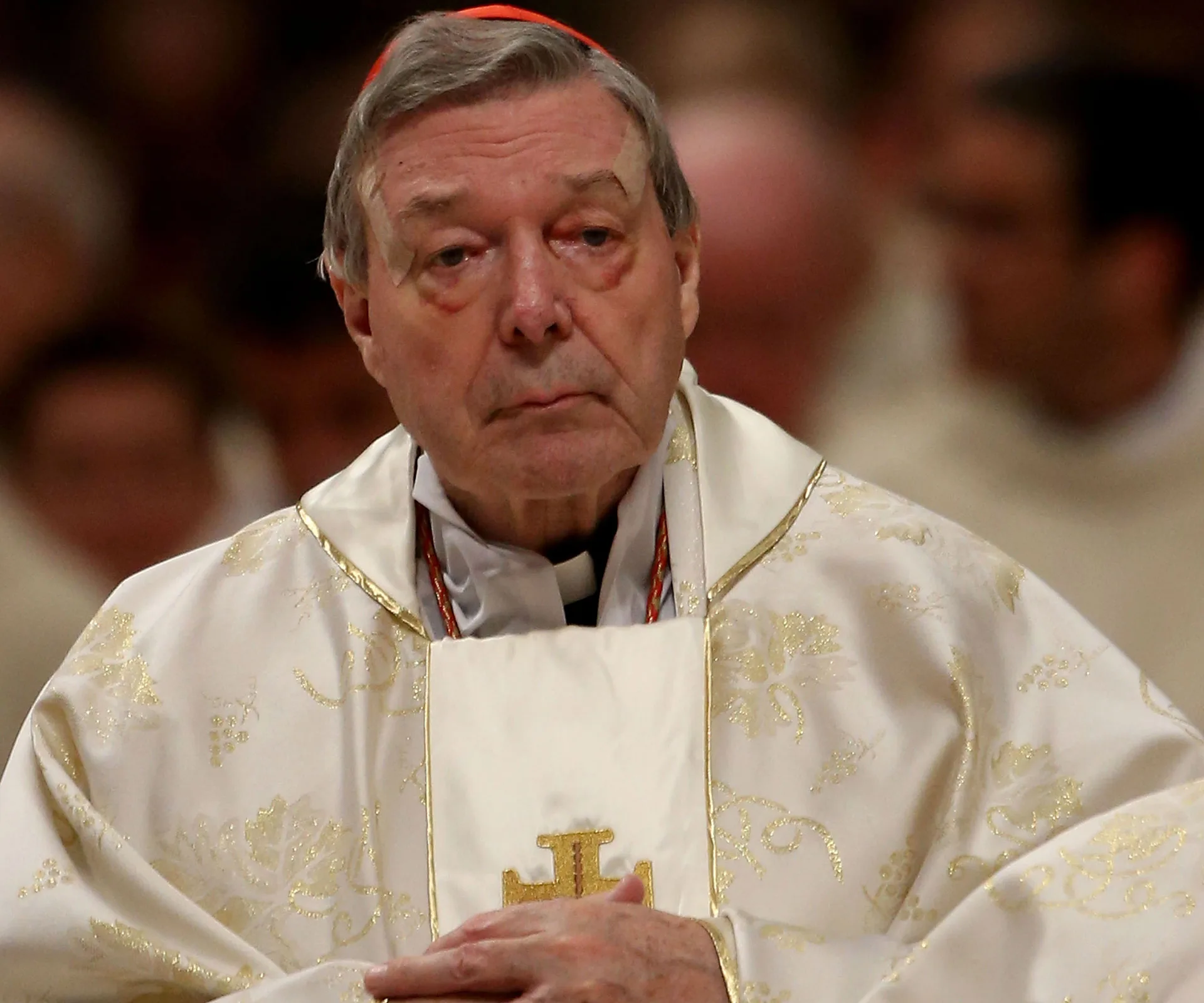 A clergy member in ornate vestments, solemnly looking forward during a church service.