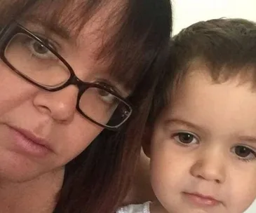 A woman with glasses and a young child looking at the camera.