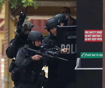 SWAT team members in tactical gear, holding rifles and a shield, standing by a fire safety door during an operation.