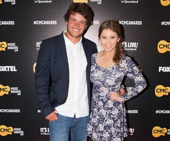Couple smiling at the CMC Music Awards, posing on the red carpet in formal attire.