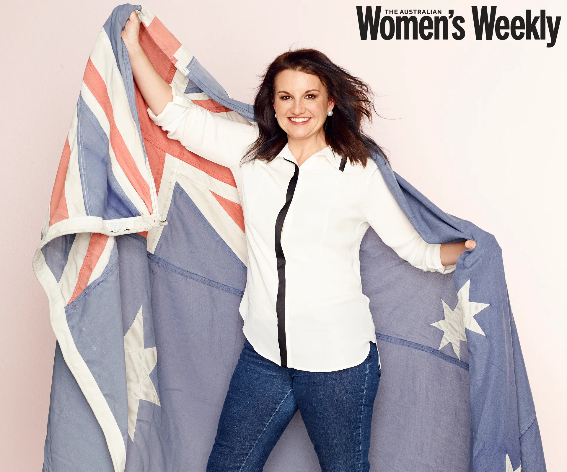A woman in a white shirt holds an Australian flag while smiling, with "The Australian Women's Weekly" in the top corner.