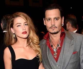 Amber and a man at a formal event, Amber in a black dress, and the man in a gray suit with red accents.