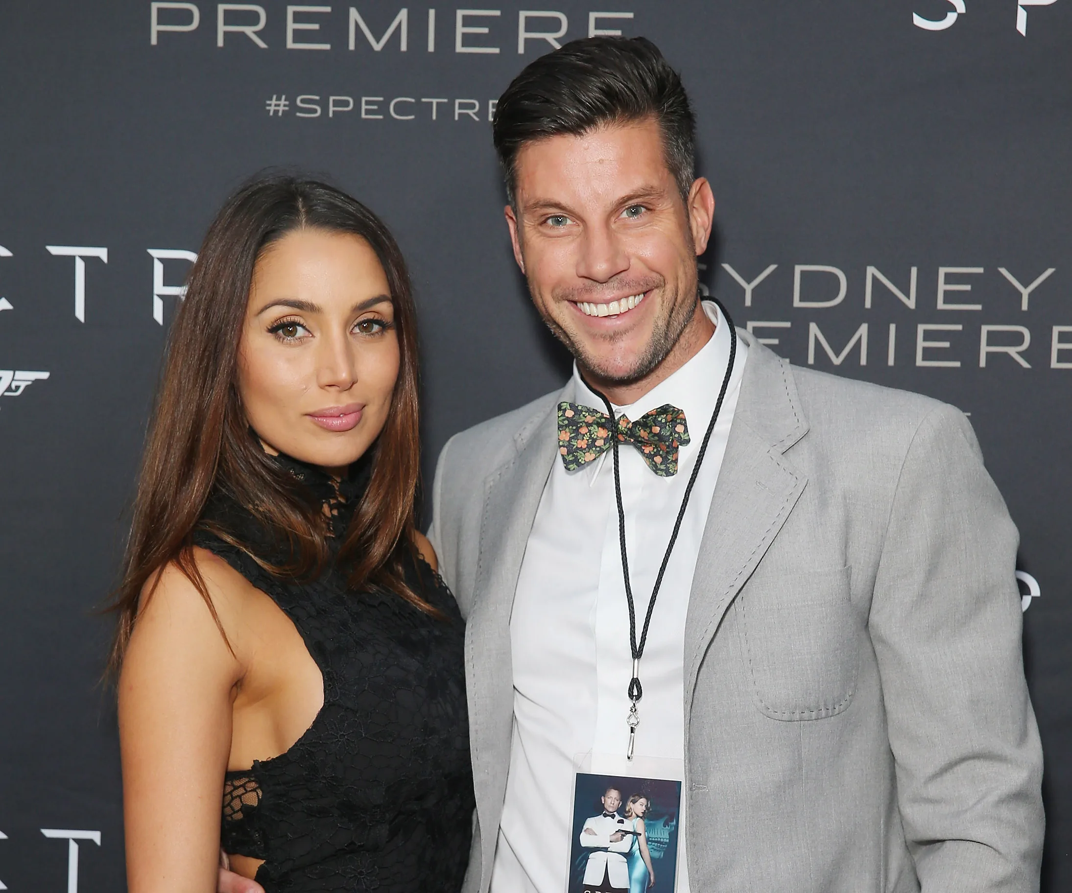Couple poses at the Sydney premiere of "Spectre," with both smiling against a backdrop featuring the film's logo.