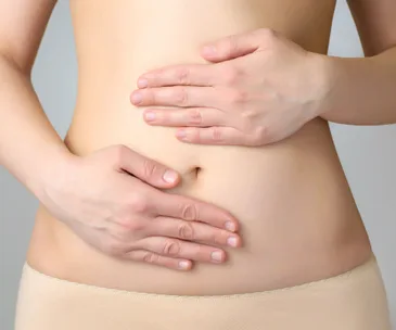 Woman holding her lower abdomen, possibly indicating pain or discomfort related to endometriosis.
