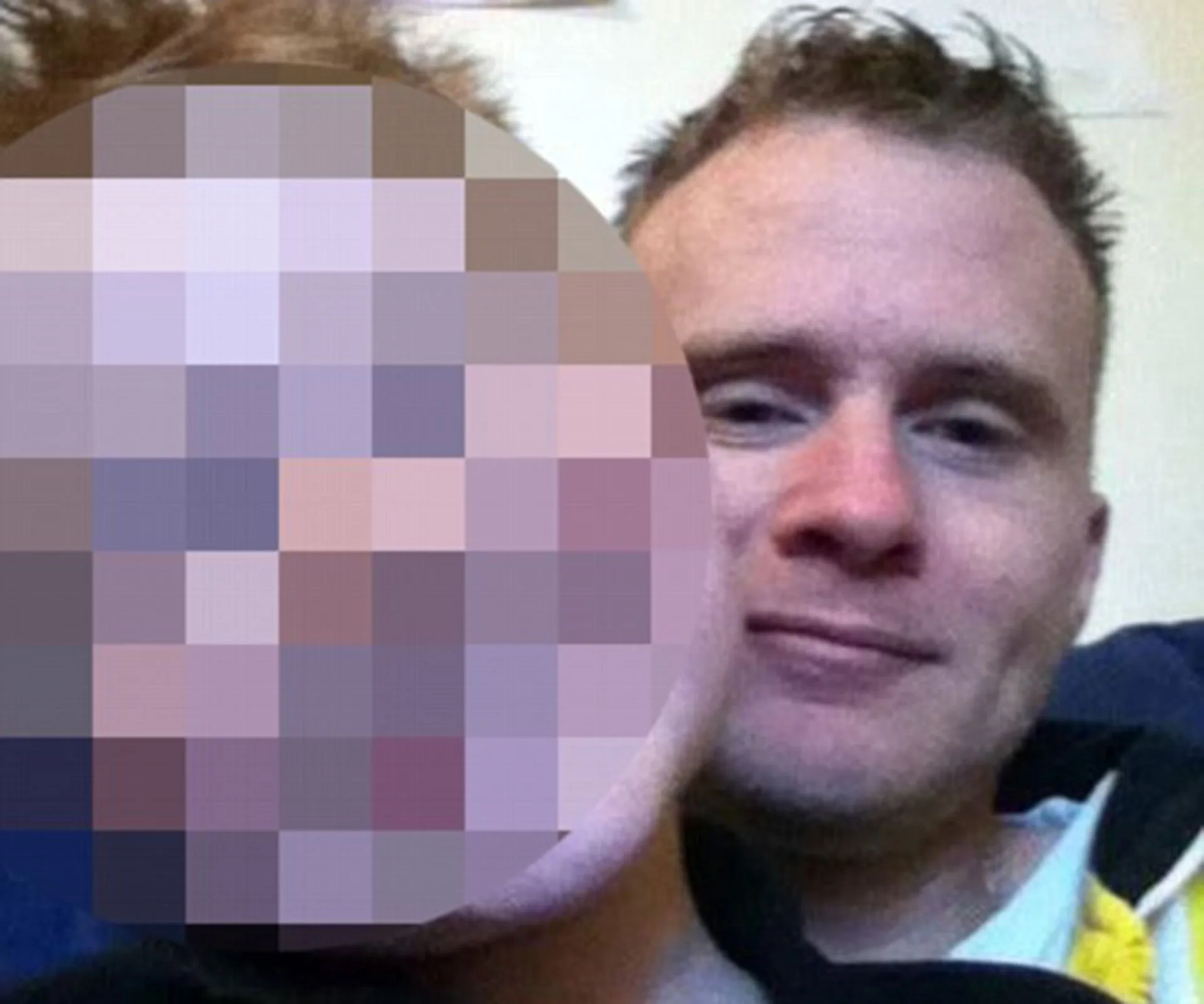 A man is seen smiling with another person's face pixelated beside him.