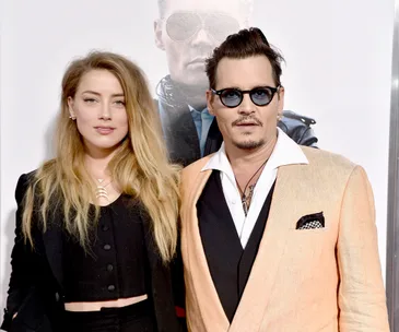 Amber Heard and Johnny Depp at a formal event with a poster background.