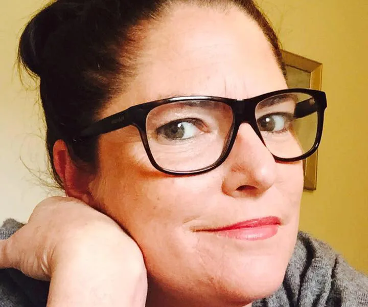 A person wearing glasses, looking at the camera with a neutral expression.