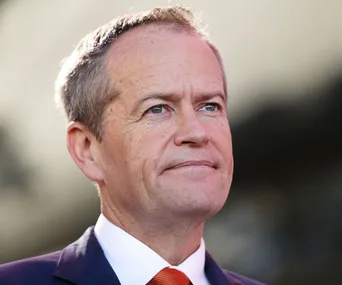 A person in a suit and red tie looking into the distance with a thoughtful expression.