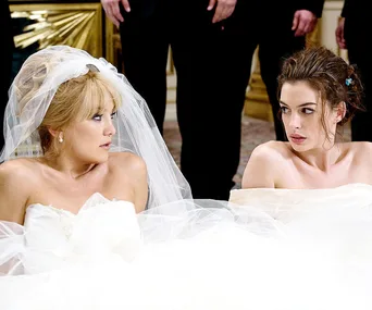 Two brides in wedding dresses looking at each other with tense expressions, surrounded by onlookers.
