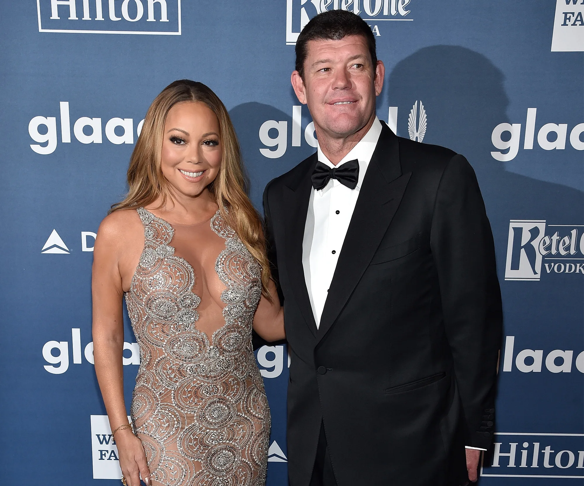 Couple in formal attire at GLAAD event; woman in a detailed dress, man in a tuxedo, posing on the red carpet.