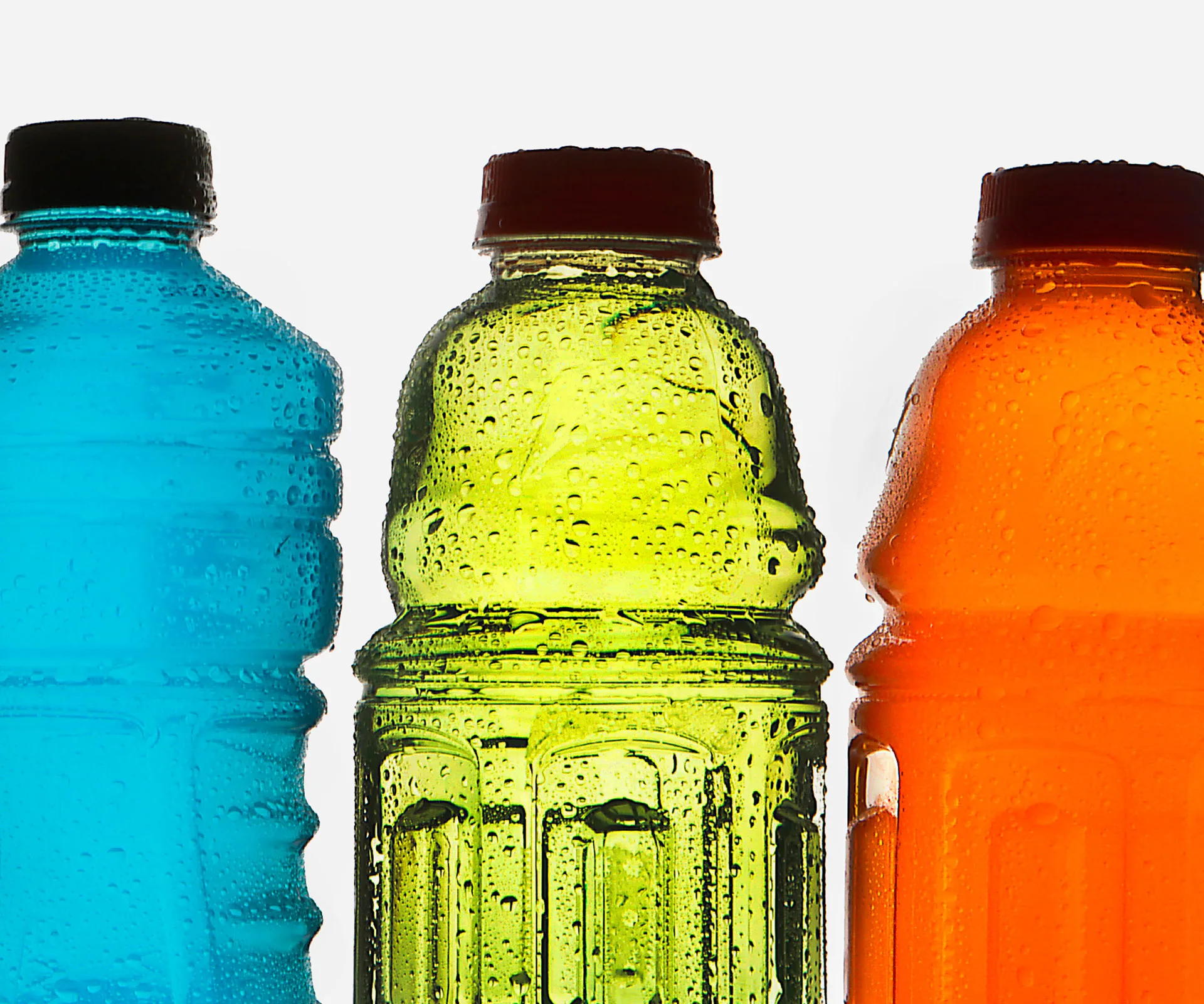 Three colorful sports drink bottles in blue, green, and orange with condensation on them against a white background.