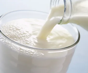 Pouring raw milk into a glass, showing bubbles and texture.