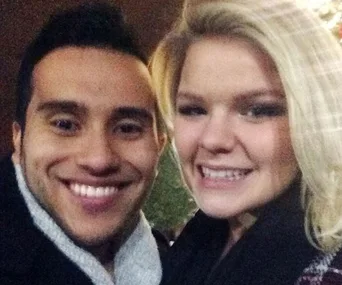 Young couple smiling together in a close-up selfie, wearing warm clothing outdoors.