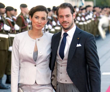 Prince Felix and Princess Claire of Luxembourg with military personnel in the background.