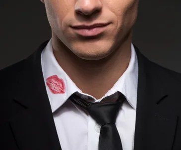 Man in suit with lipstick stain on collar, hinting at infidelity.