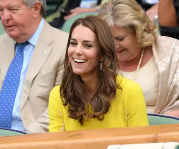 Duchess in yellow dress smiling at Wimbledon, surrounded by spectators.