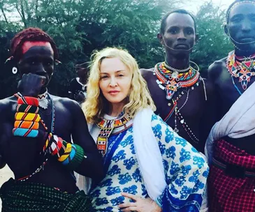 Madonna poses with Masai tribal members in Africa, wearing traditional beaded clothing and jewelry.