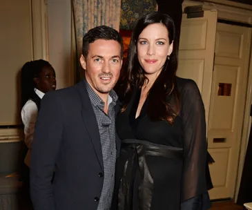 Man and woman smiling together indoors at an event.