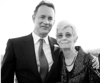Man in a suit with an older woman in glasses, both smiling, black and white photo.