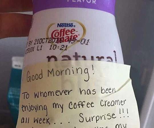 Hand holding coffee creamer bottle with note warning fridge thief about breast milk swap as revenge.