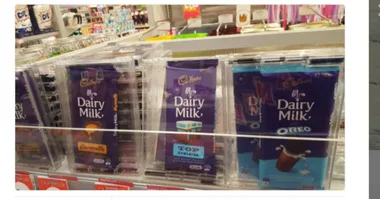 Cadbury Dairy Milk chocolates in locked plastic cases on store shelf for security.
