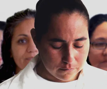 A solemn person with closed eyes in focus, with blurred individuals in the background.