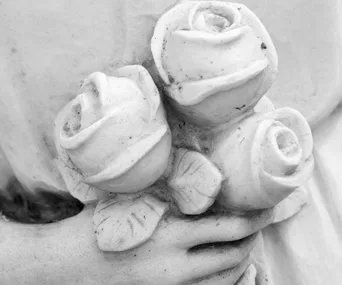 Close-up of a stone sculpture of a hand holding three roses.