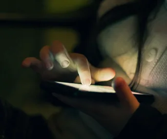 "Close-up of a person using a smartphone in dim light."