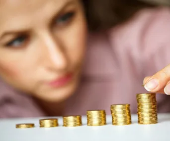 A person stacking coins in ascending order, symbolizing financial growth or investment strategy.