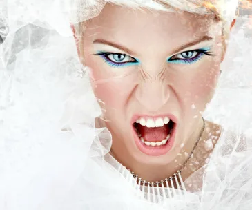 Angry bride with vivid makeup, open mouth, and veil, expressing frustration.