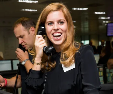 Smiling woman on the phone at a busy office event.