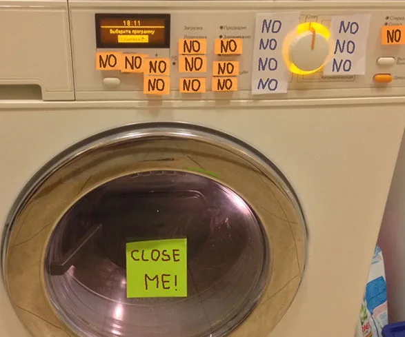Washing machine with sticky notes saying "NO" around the controls and "CLOSE ME!" on the door.